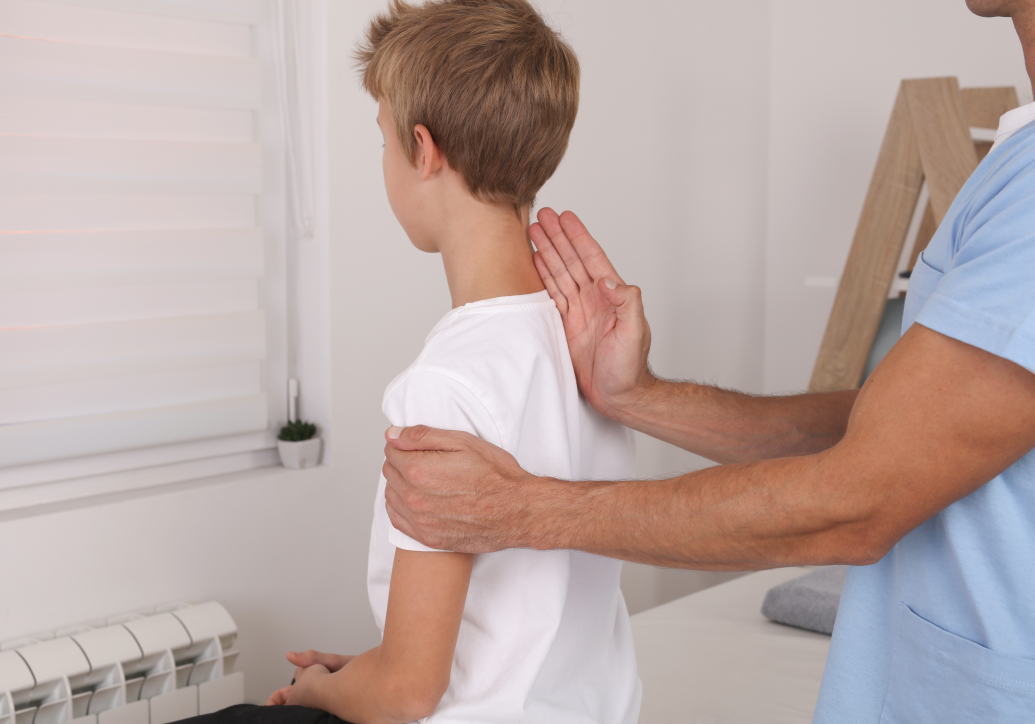 child sitting on table being examined by Scoliosis Chiropractors